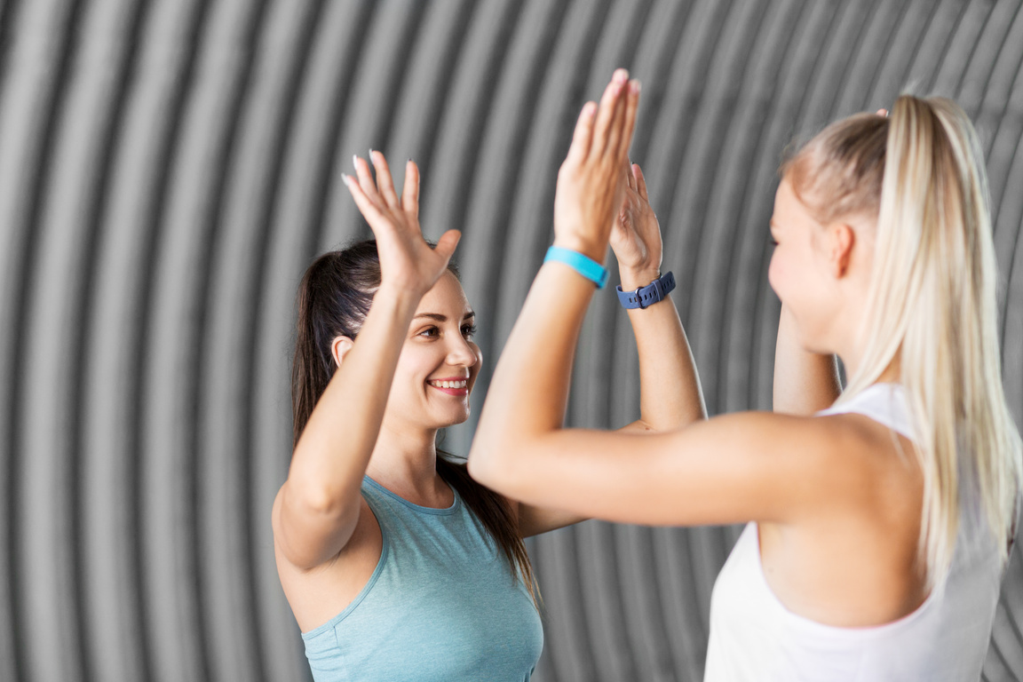 Happy Women with Fitness Trackers Making High Five